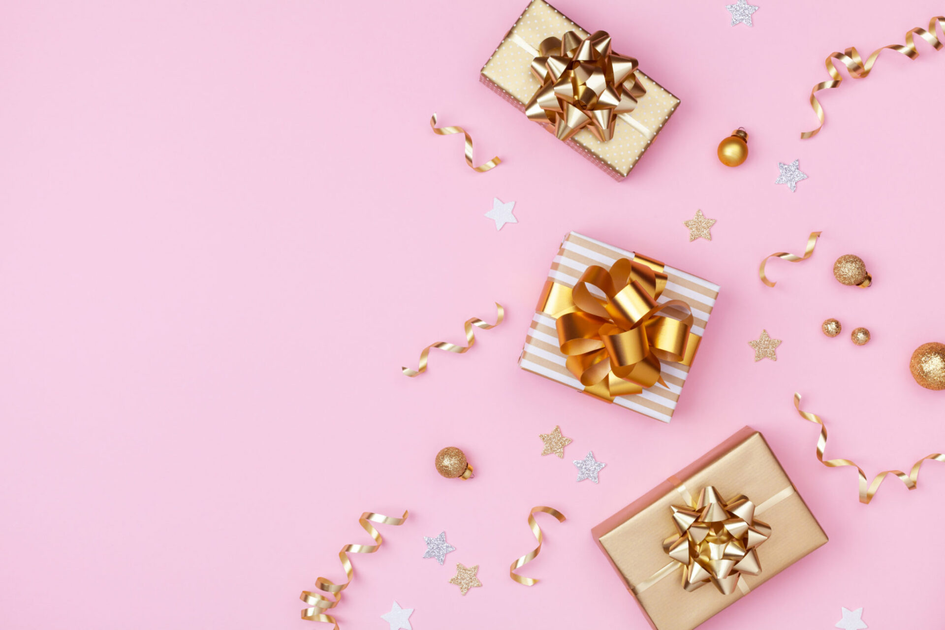 Golden gift or present boxes and Christmas decorations on pink background top view. Flat lay.